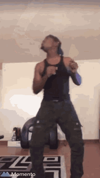 a man in a black tank top is dancing in a room with the word momento on the bottom