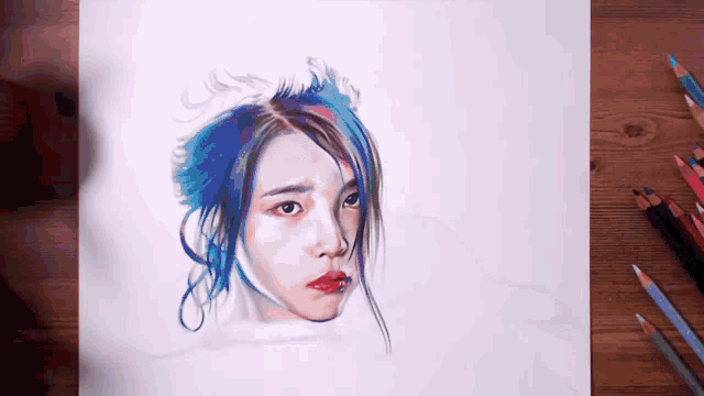 a drawing of a woman with blue hair is on a table with colored pencils