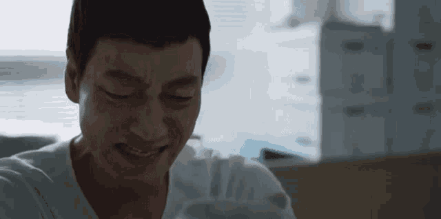 a man in a hospital gown is smiling with his eyes closed
