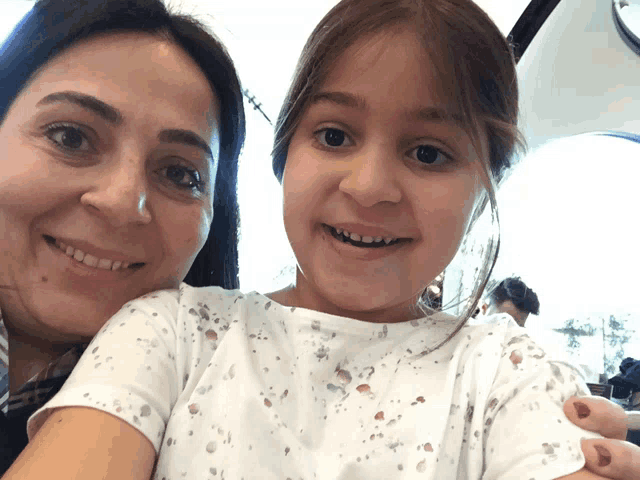 a woman holds a little girl who is smiling for the camera