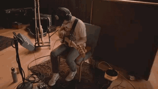 a man wearing headphones is playing a guitar in a dark room