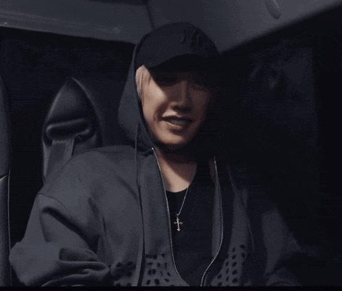 a man wearing a ny hat and a hoodie is smiling