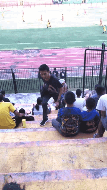 a group of people sitting on stairs in a stadium watching a soccer match