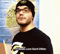 a man wearing glasses and a beanie is standing in front of a map that says " friends love each other "