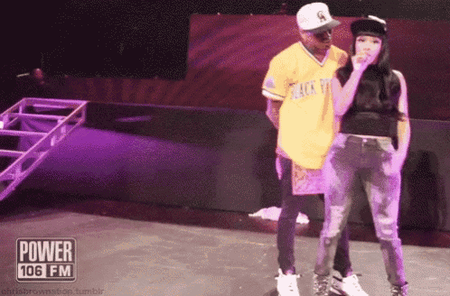 a man and a woman are standing on a stage with a power 106 fm logo in the background