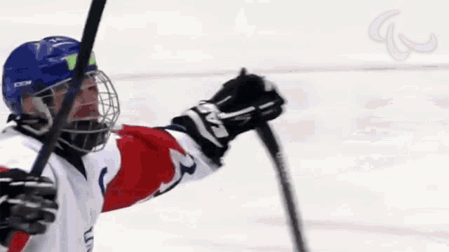 a hockey player wearing a ccm helmet holds up his stick