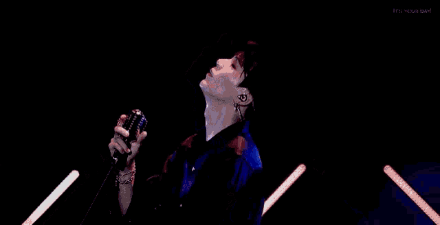 a man is singing into a microphone while playing a guitar on stage .