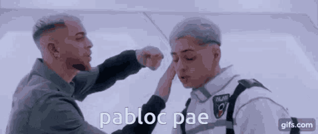 two men are standing next to each other and one of them is putting his hand on the other 's face .