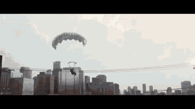 a person is flying through the air with a parachute over a city .