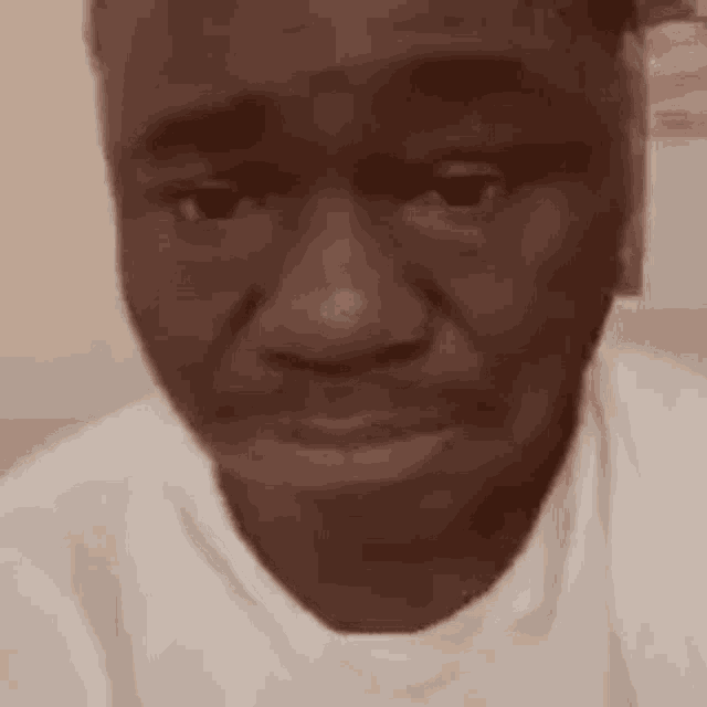a close up of a man 's face with a white shirt on making a funny face .