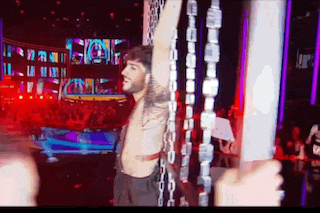 a shirtless man is chained to a pole in front of a crowd at a concert .
