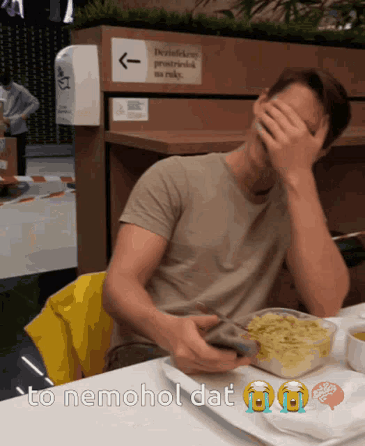 a man sits at a table with his hand on his face and the words to nemohol dat written below him