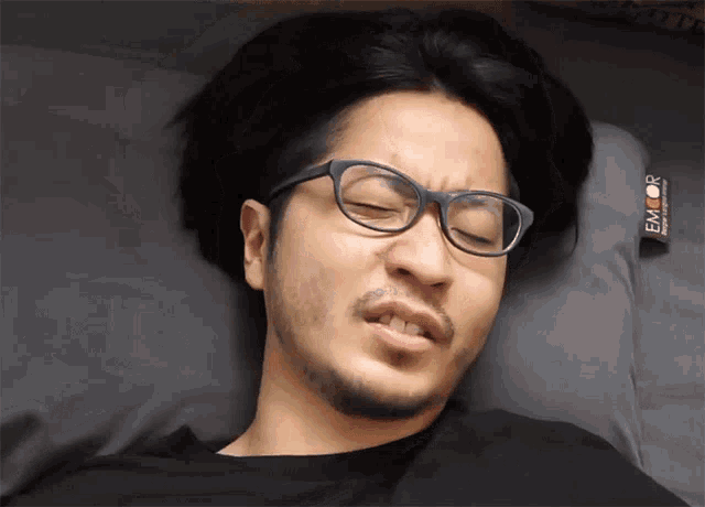 a man wearing glasses is laying on a pillow that says emcor