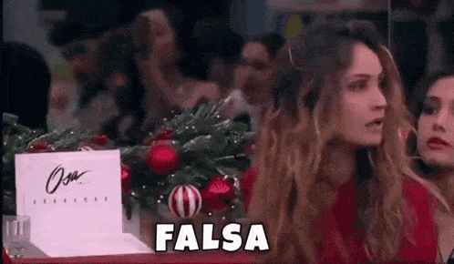 a group of women are sitting at a table with a sign that says falsa .