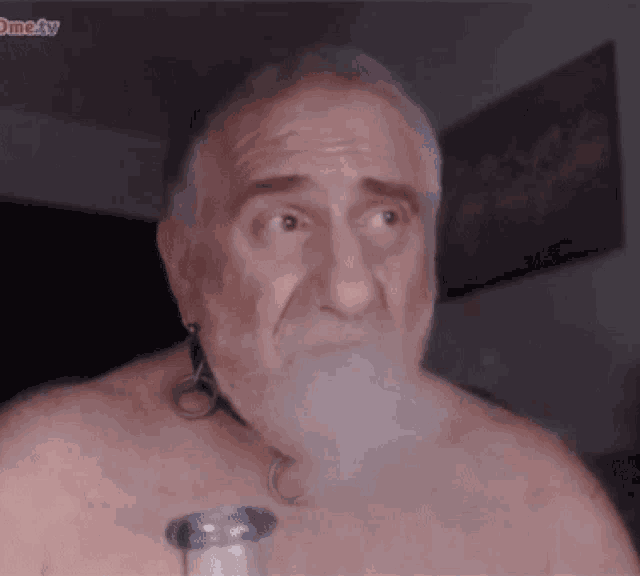 a shirtless man with a beard is smoking a cigarette and the word ome4tv is visible in the corner