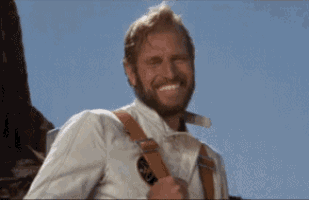 a man with a beard is smiling while wearing suspenders and a white shirt .