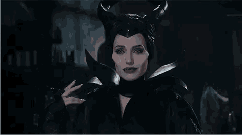 a woman in a maleficent costume with horns and a knife is smiling .