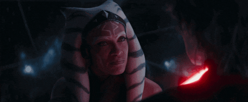 a woman is holding a red lightsaber in her hand .