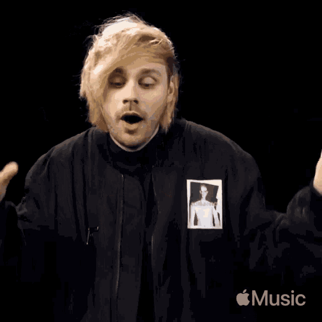 a man with blonde hair is wearing a black jacket with a picture of a man on the front .