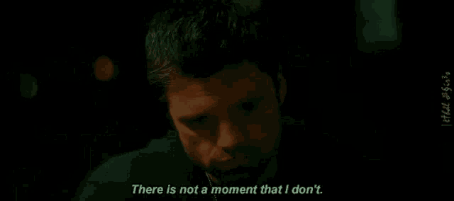 a man is sitting in a dark room and talking to someone .