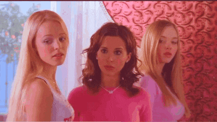 three women are standing next to each other in a room wearing pink clothes .
