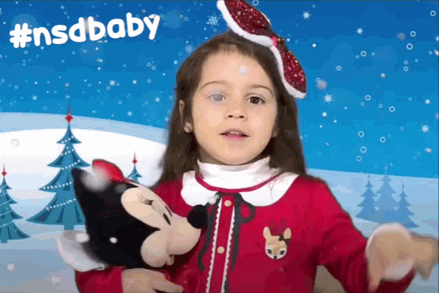 a little girl holding a stuffed minnie mouse in front of a #nsdbaby banner