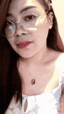 a woman wearing glasses and a necklace with the letter a on her neck