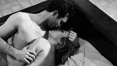 a man and a woman are laying on a couch kissing .