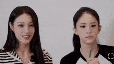 two young women are standing next to each other and smiling .