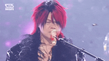 a person with red hair is singing into a microphone