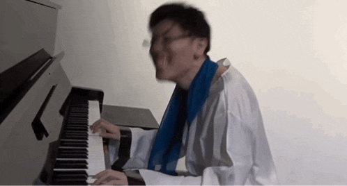 a man wearing a white shirt and a blue scarf is playing a piano .