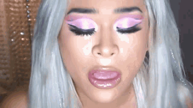 a close up of a woman 's face with pink makeup on her eyes and lips