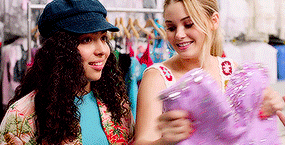 two women are standing next to each other in a store looking at a purple item .