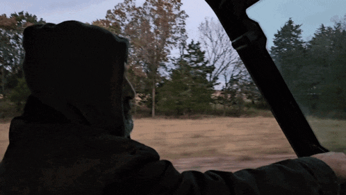 a man in a black hoodie is driving a vehicle
