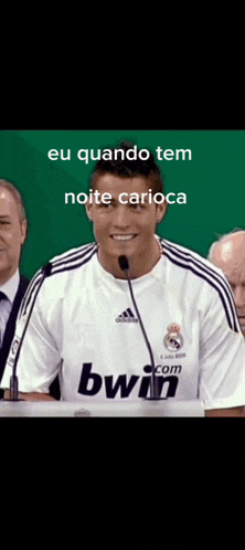 a man wearing a white bwin jersey stands in front of a microphone