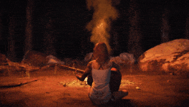 a woman playing a guitar in front of a campfire