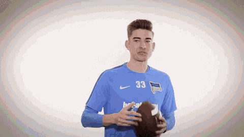 a man in a blue shirt with the number 33 on it holds a football