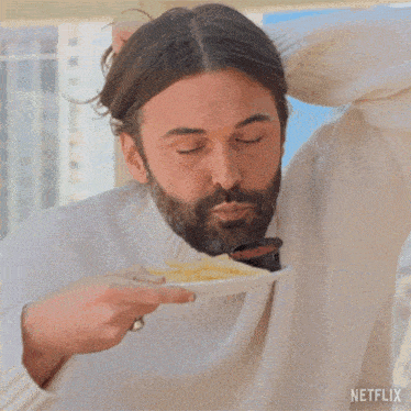 a man in a white sweater is eating french fries from a plate with a netflix logo on the bottom