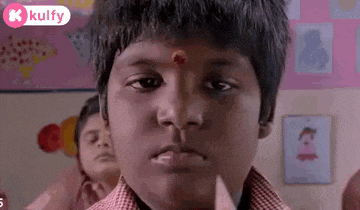 a young boy with a red bindi on his forehead is looking at the camera .