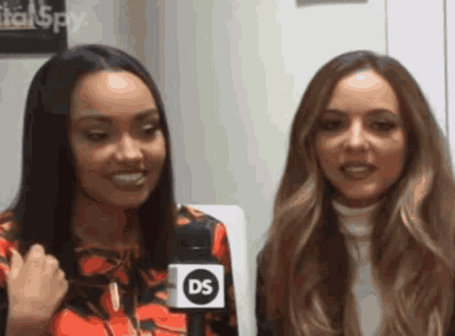 two women are standing next to each other with a microphone that says ds on it .