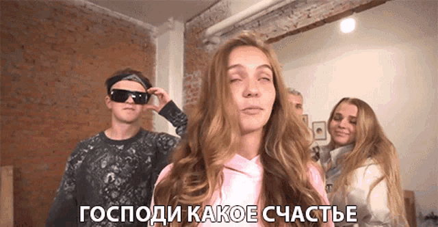 a girl in a pink hoodie stands in front of a man wearing sunglasses and a sign in russian that says god