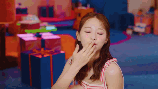 a woman is covering her mouth with her hand in front of a colorful background .