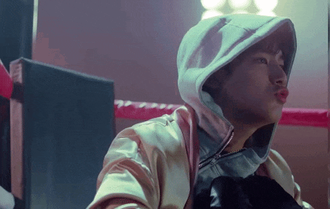 a man wearing a hoodie is sitting in a boxing ring with his eyes closed .