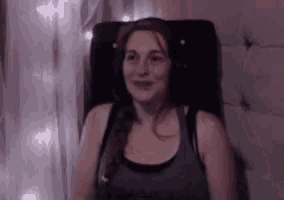 a woman wearing headphones and a tank top is sitting in a chair .