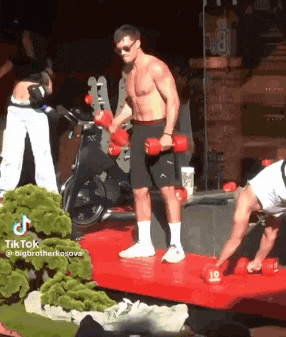a shirtless man is lifting dumbbells on a red mat with the number 10 on it .