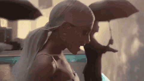 ariana grande is holding an umbrella in the rain while standing next to a pool .