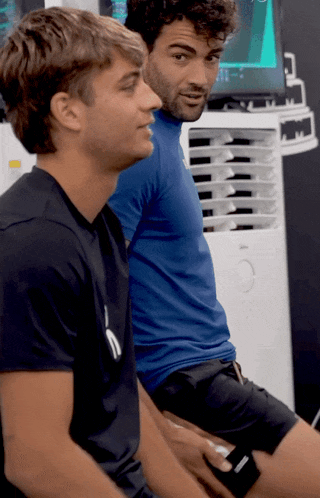 two men are sitting next to each other with one wearing a black shirt that says ' puma ' on it