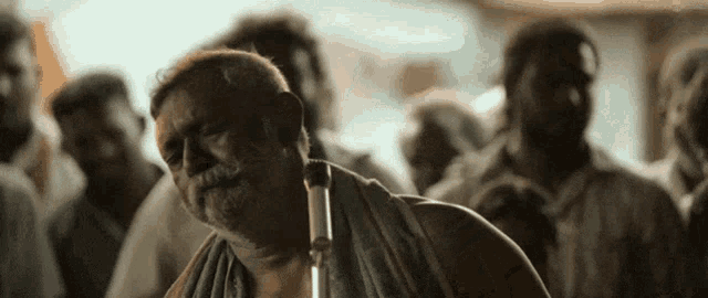 a man with a towel around his neck is standing in a crowd .