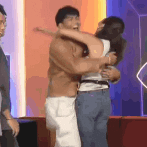 a man and a woman are hugging each other in a room .