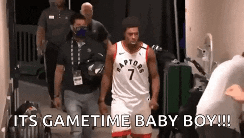a man in a raptors jersey is walking down a hallway with a group of people .
